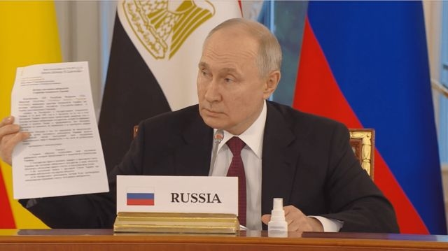 Підпис до фото,Путін під час демонстрації документів на зустрічі з делегацією з Африки