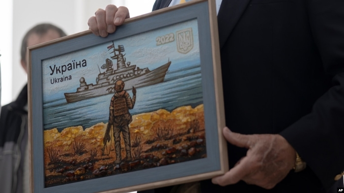 Картина із зображенням поштової марки із грубим жестом на адресу російського військового корбаля у руках голови Гельсінської комісії США Джо Вілсона, Бучі, Україна, 5 травня 2023 р. AP photo/Andrew Kravchenko