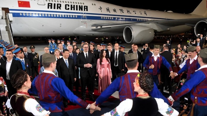 Xi Jinping, Serbian President Aleksandar Vucic and his wife Tamara Vucic stand on a red carpet in front and Air China plane on the tarmac at Belgrade Airport