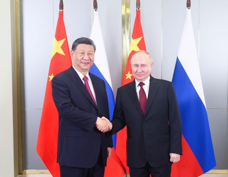 Chinese president Xi Jinping shakes hands with Russian president Vladimir Putin.