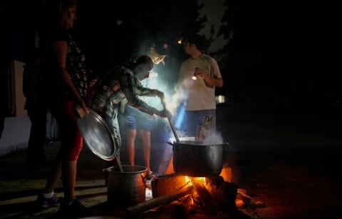 people cook outside in the dark and shine flashlights