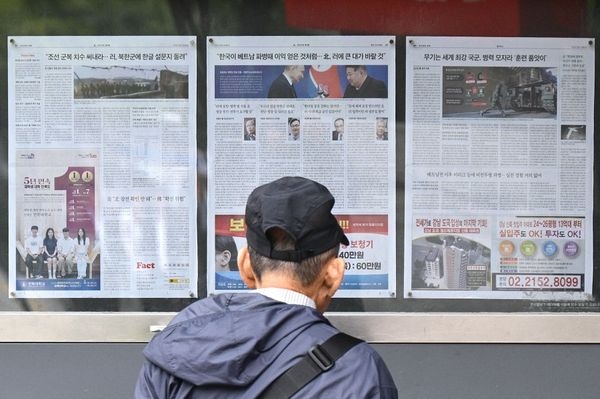 A man walks past a newspaper displayed on a street for the public in Seoul, South Korea on 21 October 2024, with coverage on North Korea’s decision to deploy thousands of soldiers to Ukraine’s front lines and a photo (centre) of North Korean leader Kim Jong-un and Russia’s President Vladimir Putin toasting at a banquet in Pyongyang earlier this year. (Anthony Wallace/AFP)