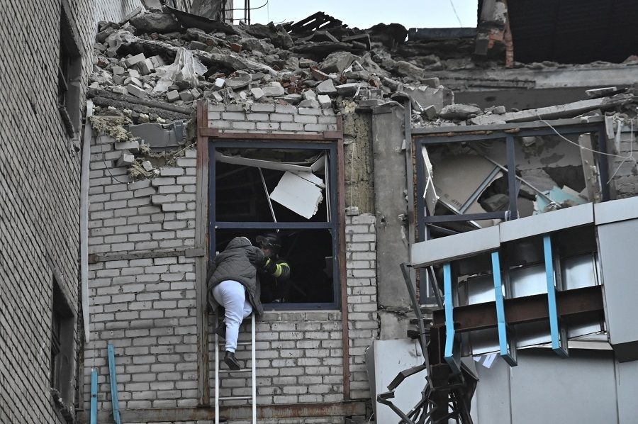 A rescuer evacuates a woman from a building heavily damaged by a Russian missile strike, amid Russia’s attack on Ukraine, in Zaporizhzhia, Ukraine, on 10 December 2024. (Stringer/Reuters)