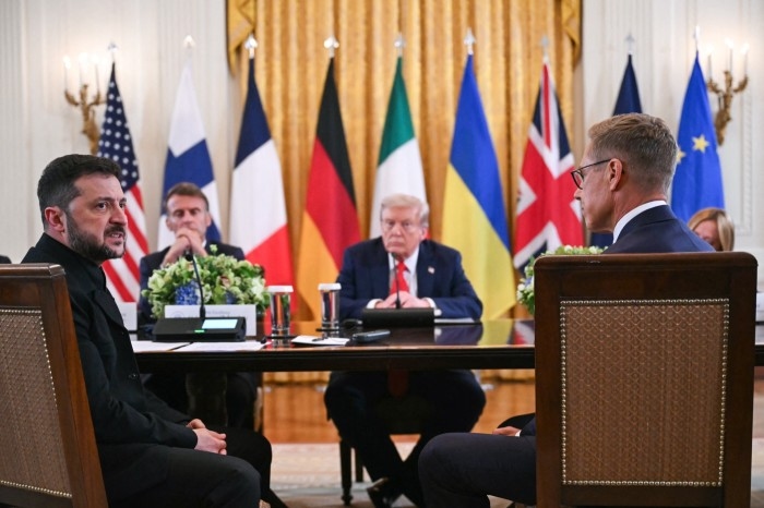 Volodymyr Zelenskyy speaks as Emmanuel Macron, Donald Trump and Alexander Stubb listen during a meeting at a conference table