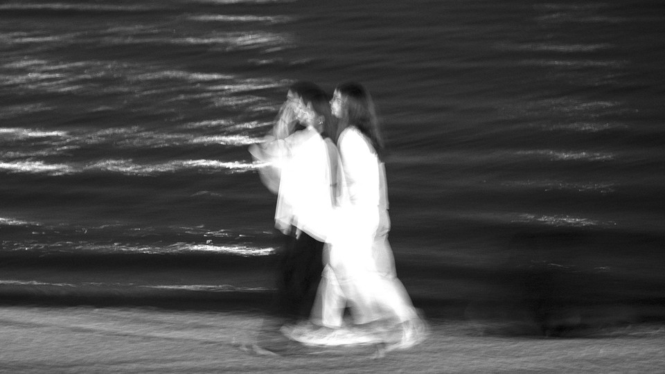 Two young Iranian women walk together along a shore of the Chitgar Lake in the recreational Chitgar complex in northwestern Tehran, Iran, on September 11, 2025.
