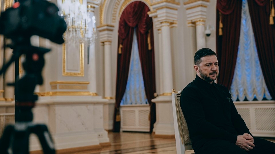 A color photograph of Zelensky seated and looking off camera during an interview