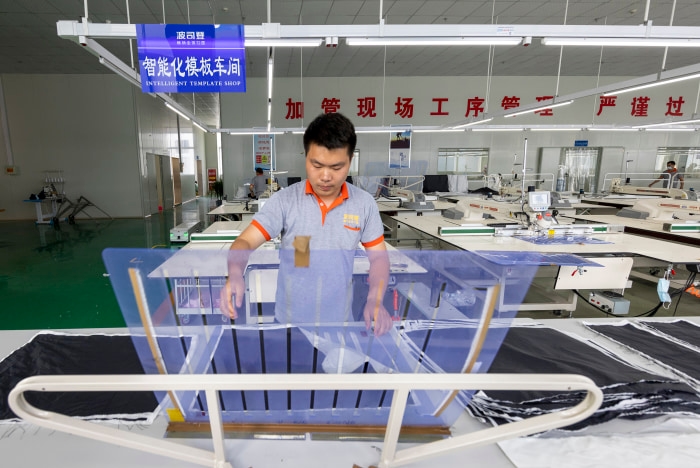 A worker in a Bosideng garment workshop operates equipment in the "Intelligent Template Shop."