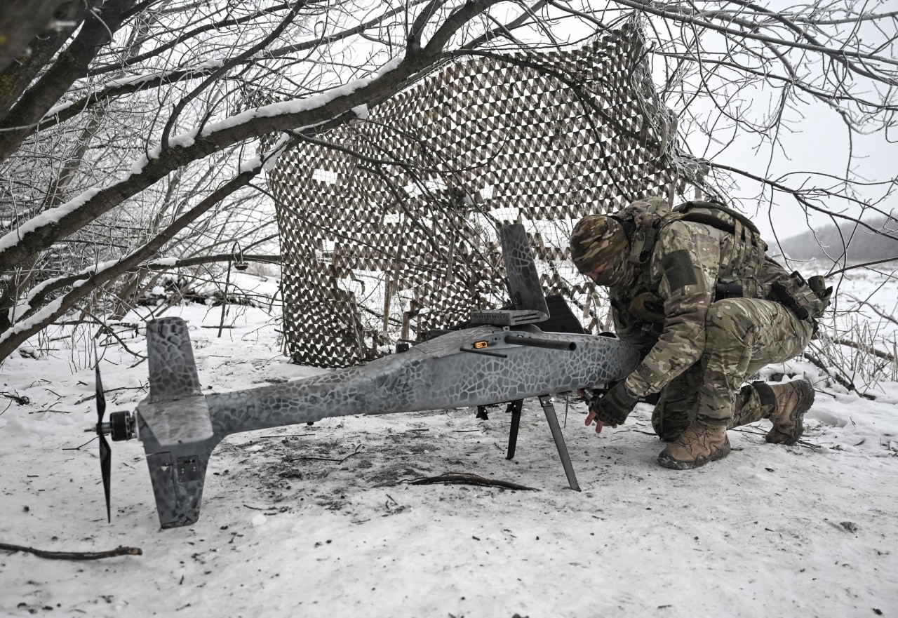 A Ukrainian soldier prepares a combat drone in the snow.