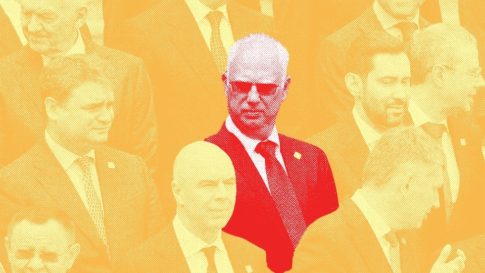 Yellow-tinted photograph of men in suits and ties with Kirill Dmitriev in the center, wearing sunglasses and colored red.