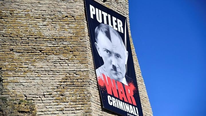 Une banderole représentant le président russe avec des traits de Hitler, au mur du musée de Narva, en Estonie. | Stringer via AFP