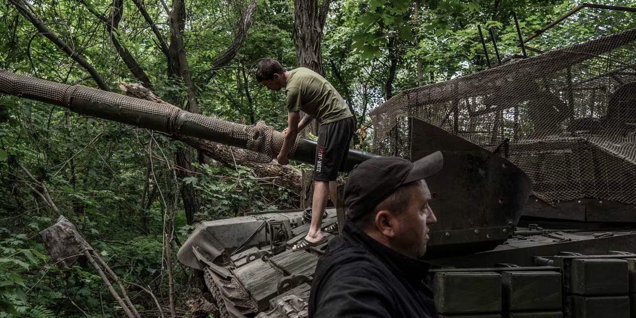 A tank crew from the 68th Jaeger Brigade performs maintenance work hidden in a line of trees in Ukraine’s Donetsk region.