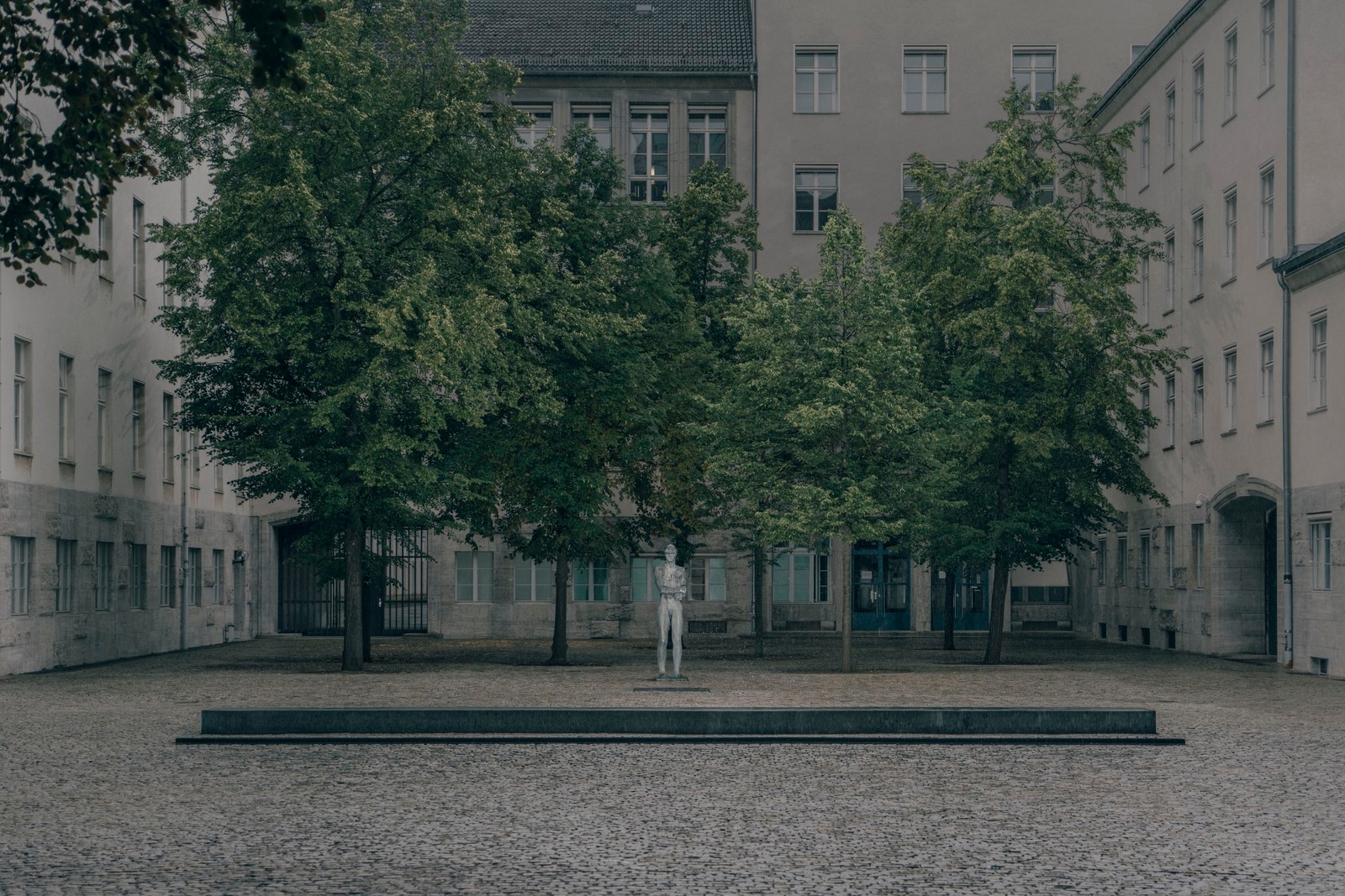 photo of a statue in an austere courtyard with trees