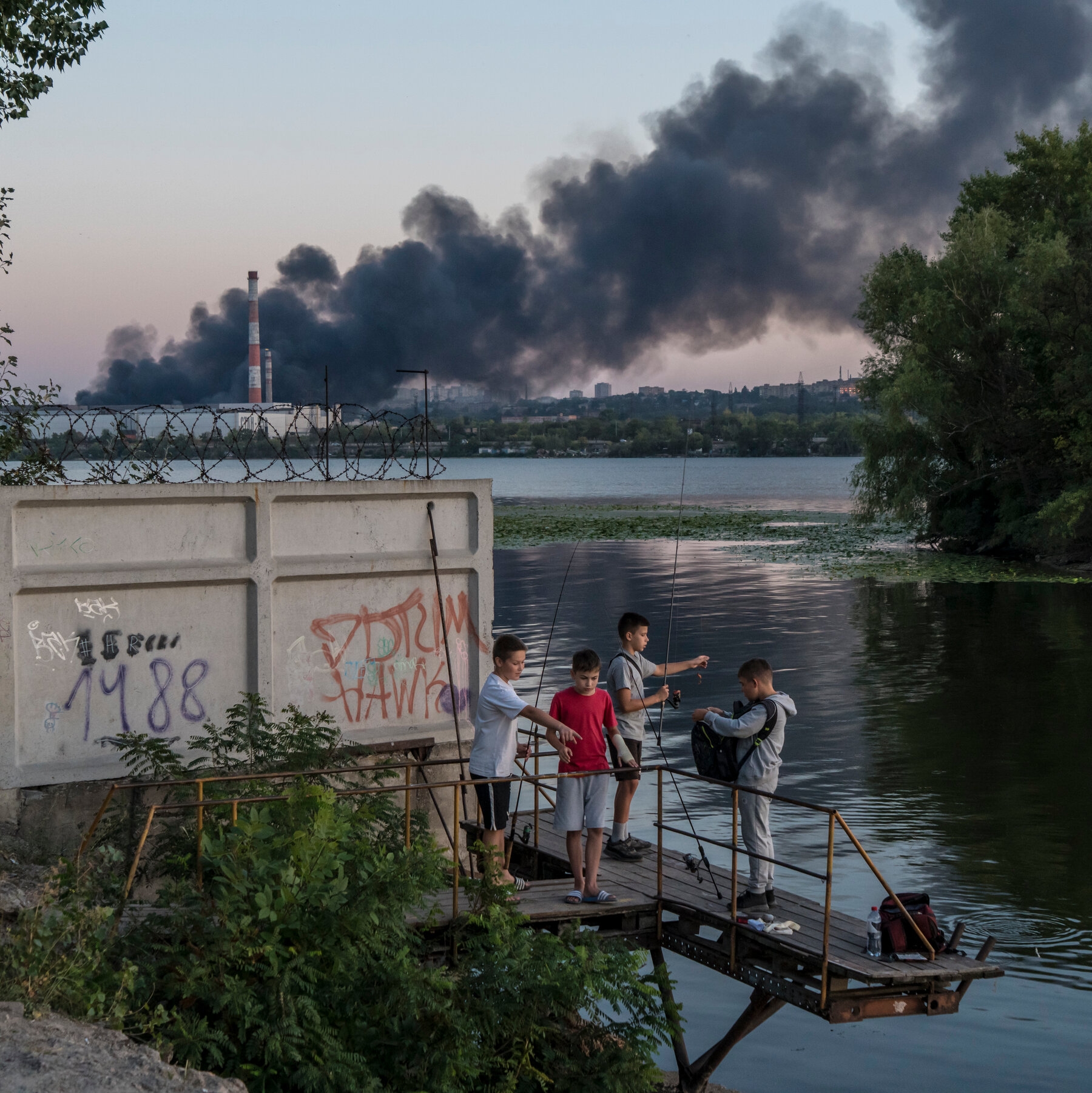 Children with fishing poles, dark smoke in the background.