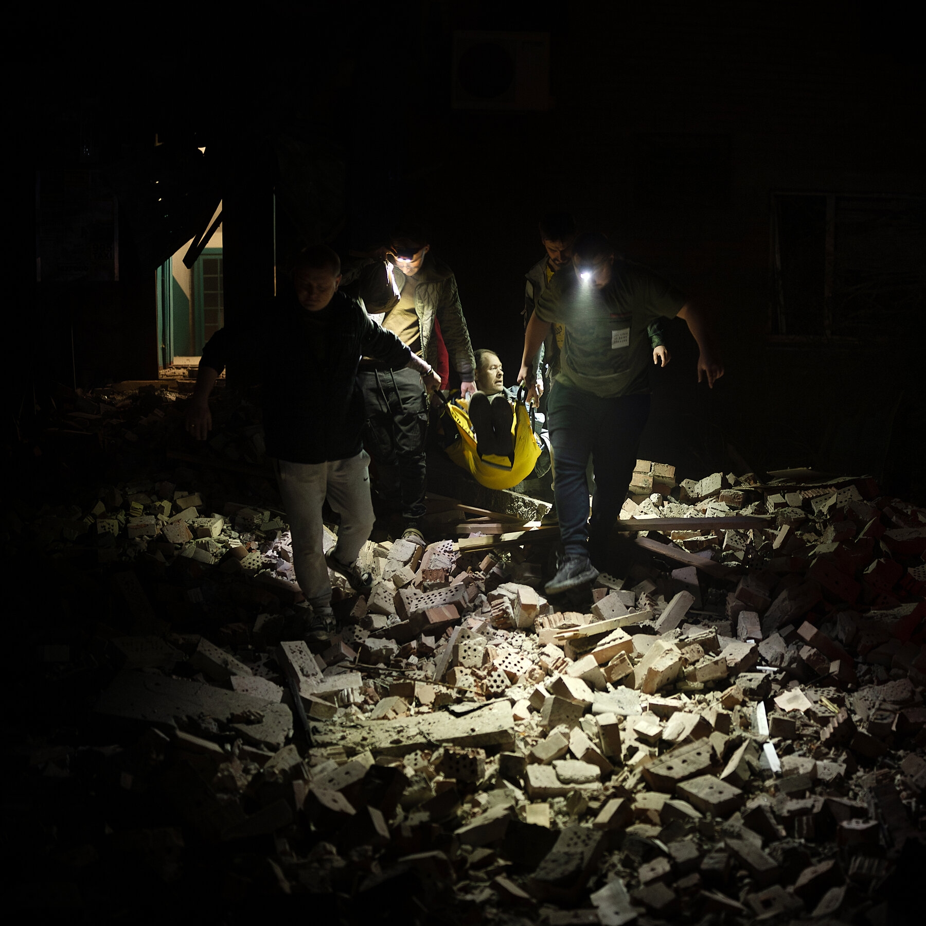 People with flashlights walking amid rubble.