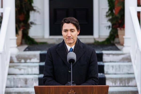 Prime Minister Justin Trudeau of Canada wears an overcoat while standing outside behind a lectern.