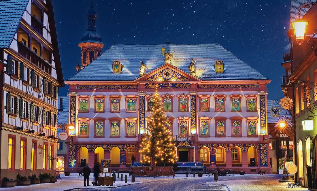 Business owners in Gengenbach, Germany, thought of turning their town hall into a giant Advent calendar more than 20 years ago to attract visitors during winter. This picture shows a three-story, neo-classical style building in the middle of a town square with a Christmas tree in front. The shades of each of the windows have been drawn up to reveal a colorful painting.  