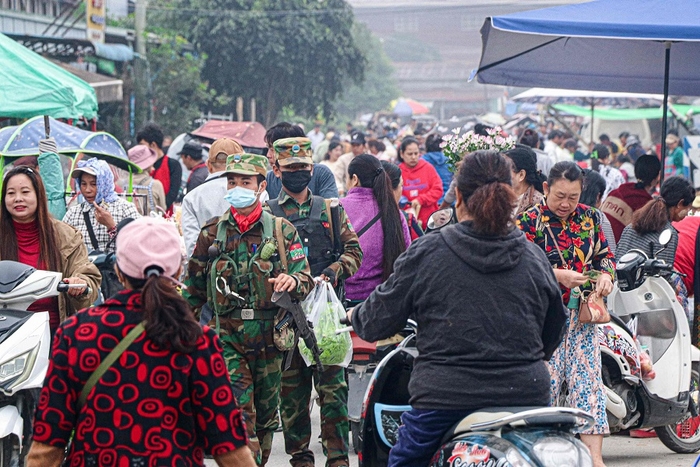 This photo taken on 10 November 2023 shows fighters of the ethnic rebel group Ta'ang National Liberation Army (TNLA) walking down a street market in the town of Namhkam in northern Shan state. (Mai Nyi/AFP)