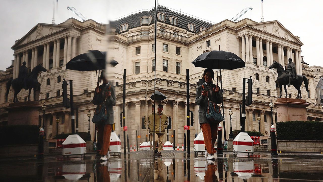 A pedestrian shelters from the rain beneath an umbrella as they walk near the Bank of England.