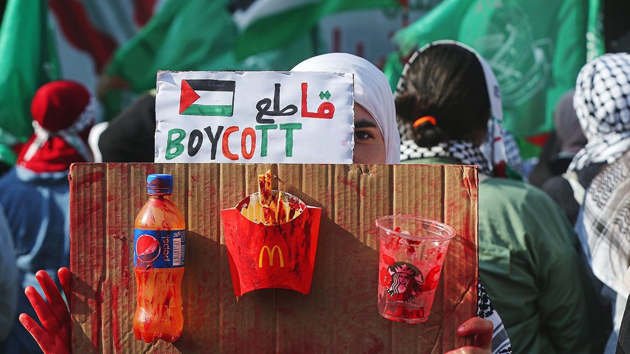 A Palestinian youth, raises a banner urging to boycott companies that allegedly support Israel during a mass rally in Beirut.