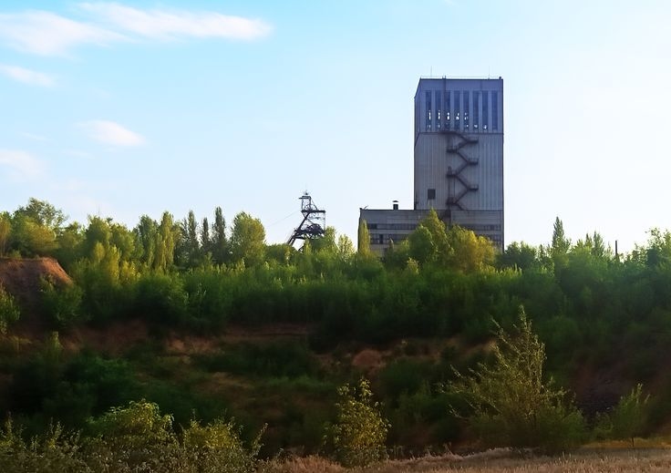 Вид на шахту та відвали породи, що вже встигли порости деревами. Внизу спуск на технічний майданчик