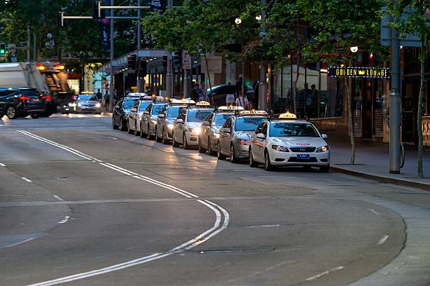 Sydney Taxi Cars Sydney, Australia - November 10, 2015: Taxi queued for passengers in Sydney CBD at night. The state of New South Wales is served by a fleet of around 6000 taxis. The industry employs over 22,700 taxi drivers. How a Sydney Entrepreneur Turned One Hatchback Into a 43-Car Fleet stock pictures, royalty-free photos & images