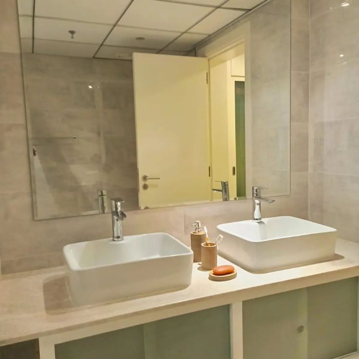 This may contain: two white sinks sitting on top of a counter next to a wall mounted faucet