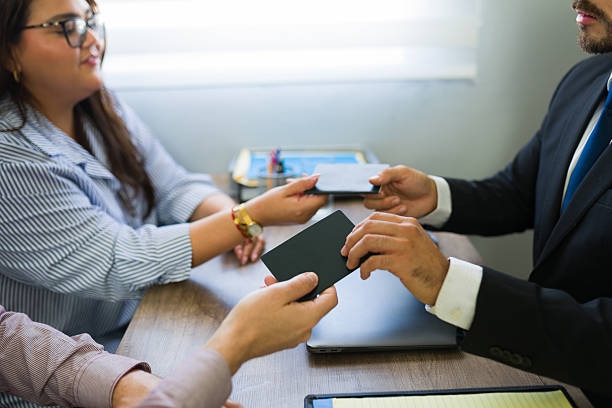 Immigrant couple receiving passports from immigration lawyer Man and woman receiving passports or documents from an attorney during a legal consultation in an office  visa consultants stock pictures, royalty-free photos & images