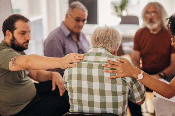 People consoling man at group therapy Diverse group of people, men and woman with problems together, consoling a man at on group therapy in circle. NDIS Support Coordination stock pictures, royalty-free photos & images